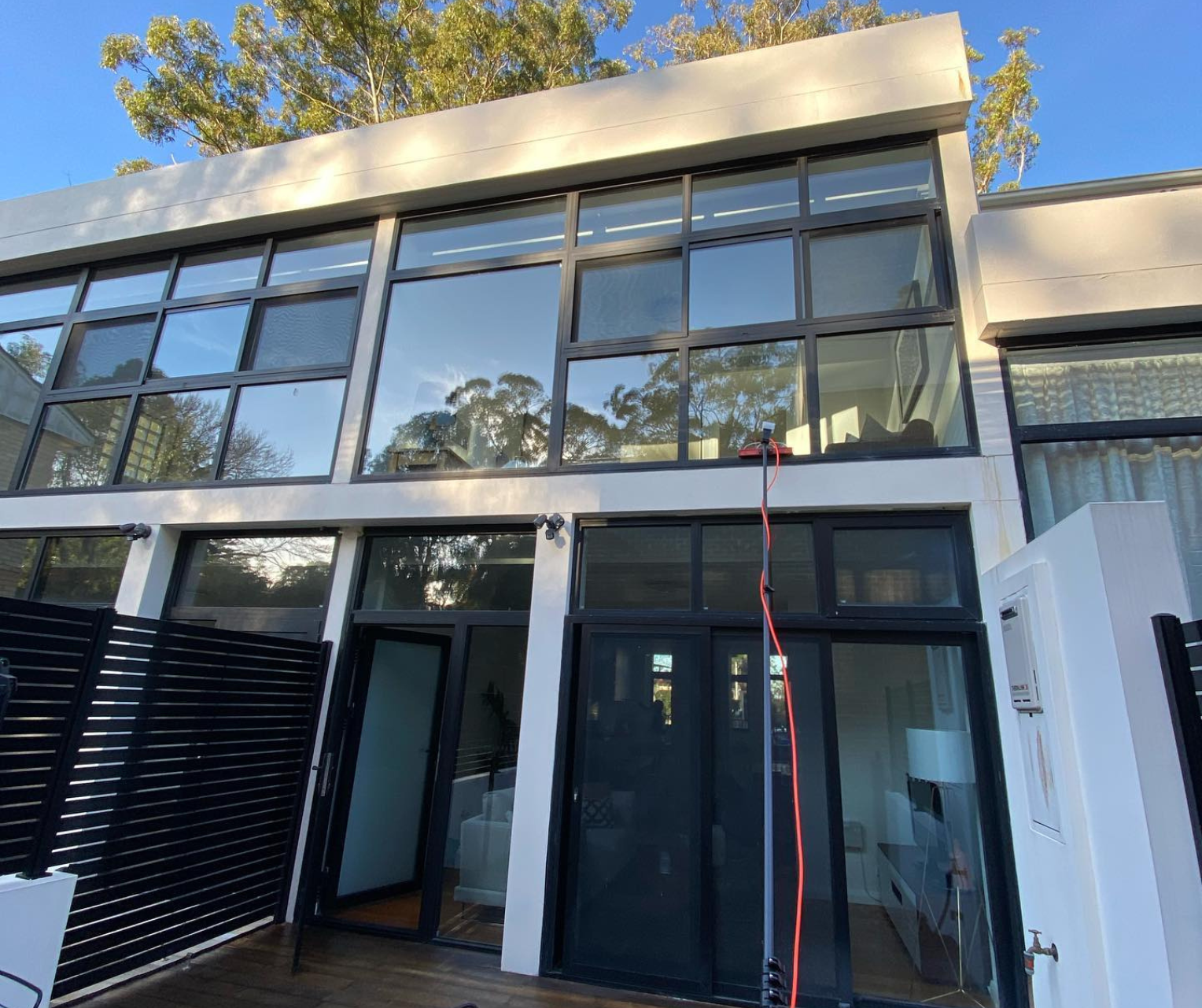 Modern glass-front building entrance with large windows and a red cable hanging down the facade Modern glass-front building entrance with large windows and a red cable hanging down the facade