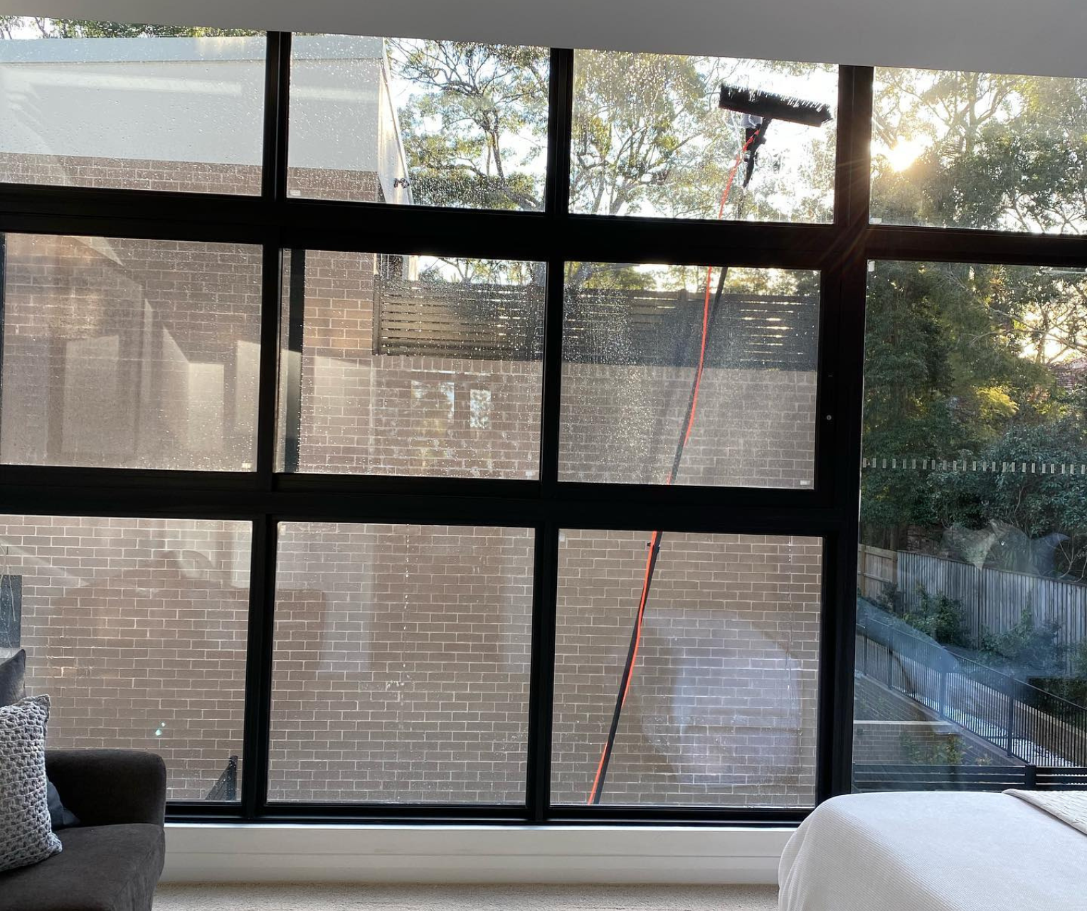 Large window with black grid framing a backyard view and a red cord hanging outside. Large window with black grid framing a backyard view and a red cord hanging outside.