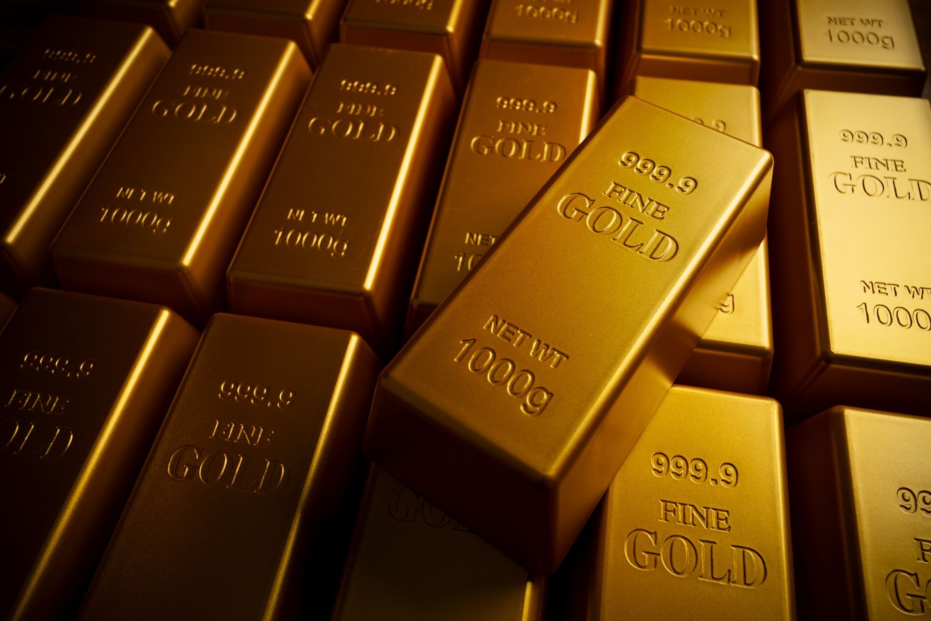 Stacked 1000g fine gold bullion bars stamped 999.9 fine gold with one bar resting on top
