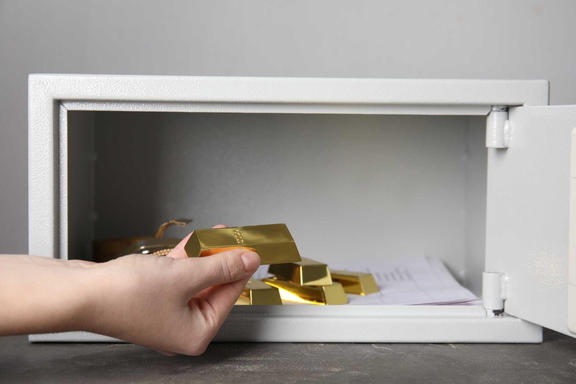 Hand taking gold bar from open safe. Hand taking gold bar from open safe.