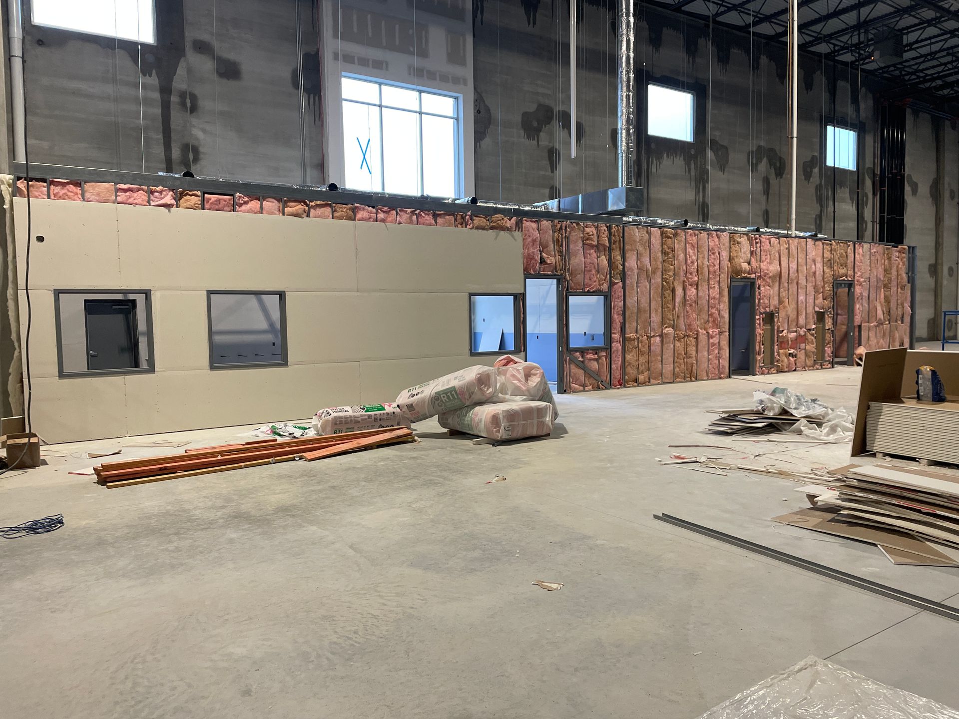 Interior construction site with unfinished walls, exposed brick, and scattered materials on a concrete floor