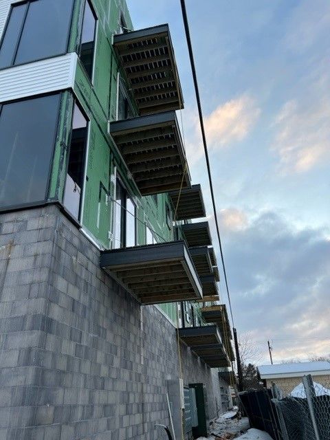 Exterior of a modern building under construction with several balconies extending outwards.