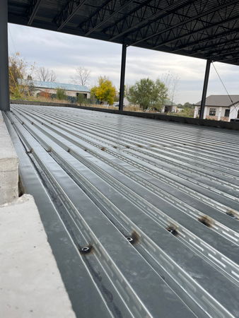 Metal decking on a building's roof under construction; exterior view with a cloudy sky.