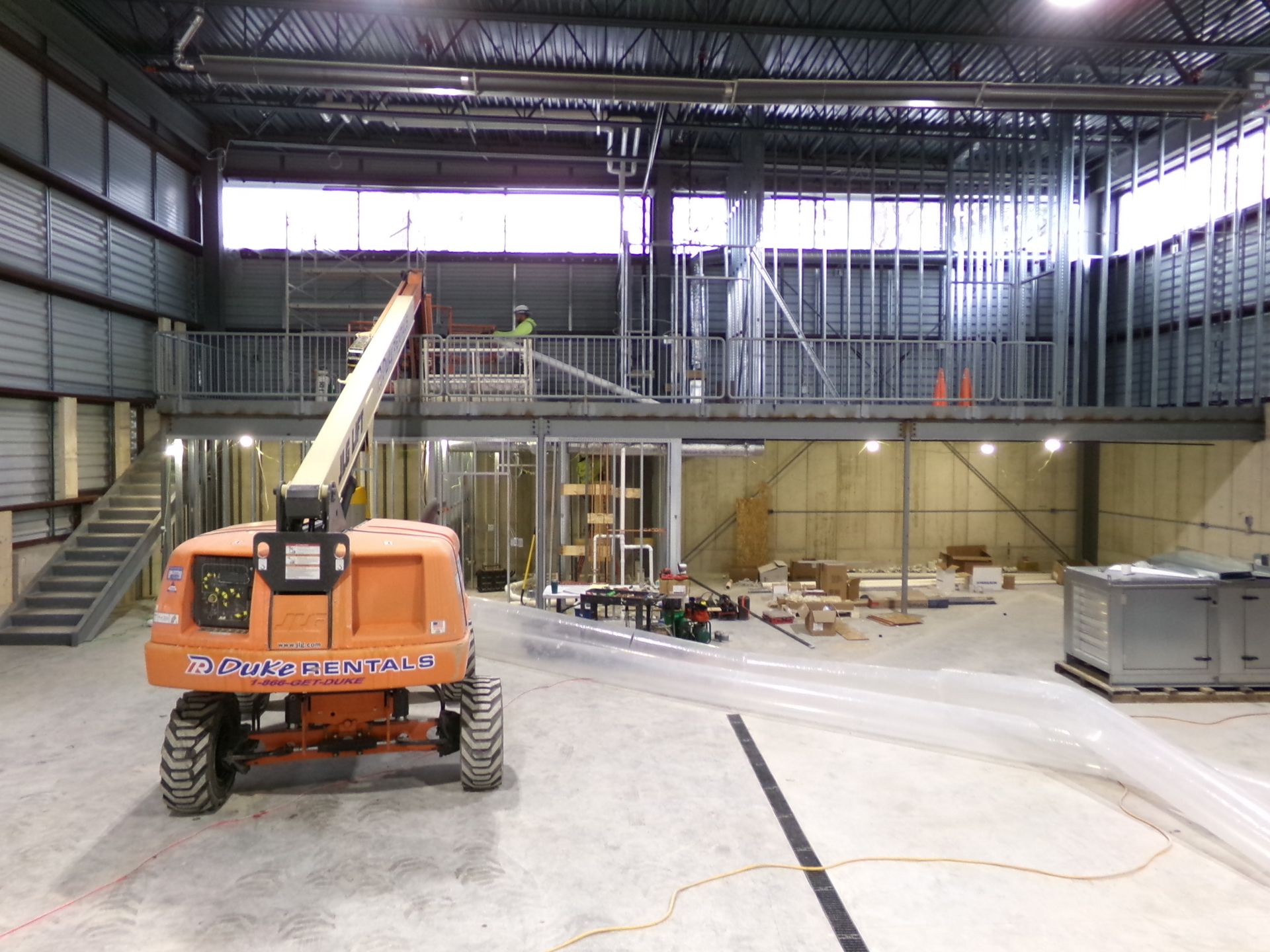 Construction site with orange lift, steel framing, and unfinished walls.