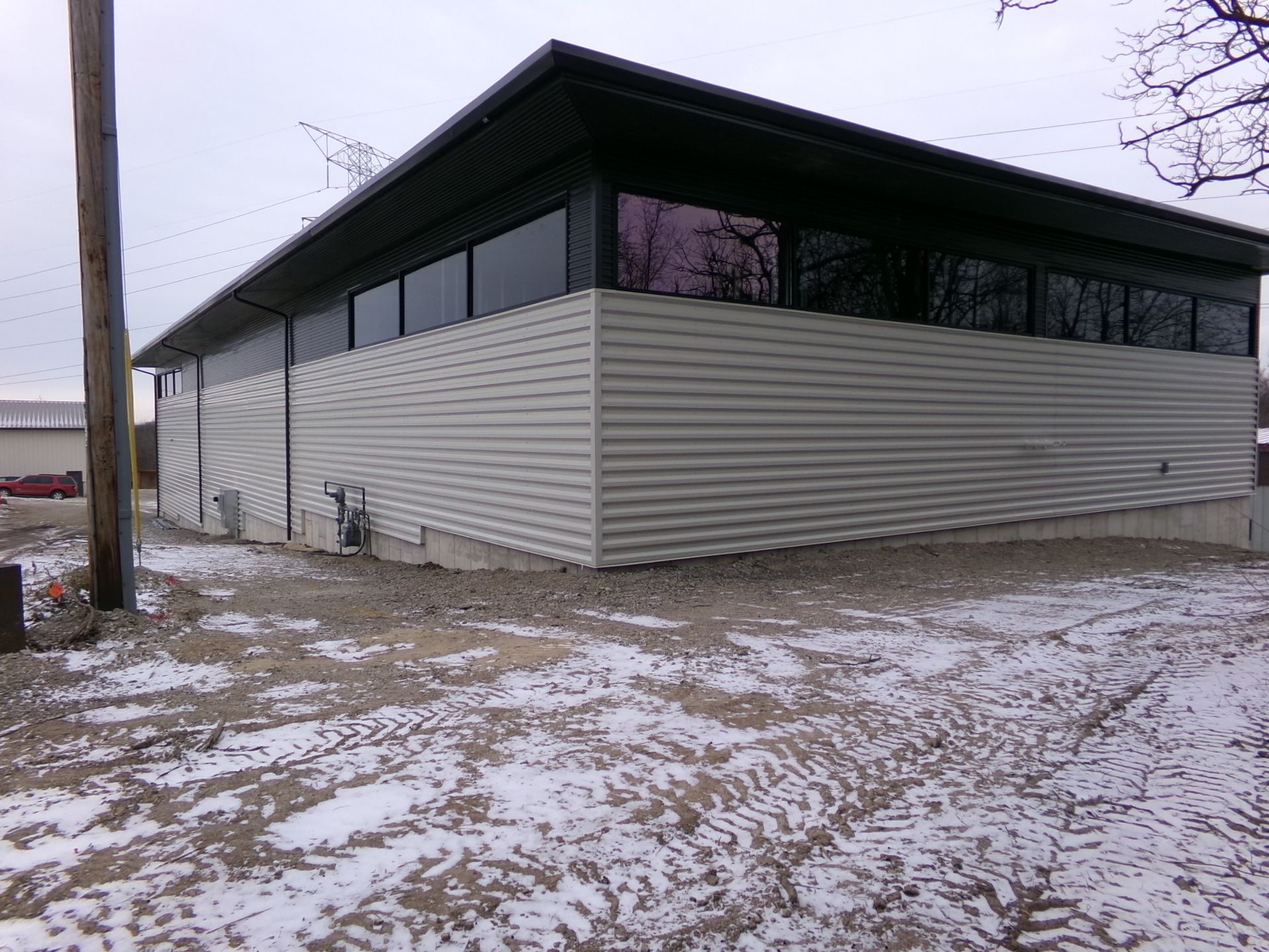 Gray industrial building with horizontal siding and windows, in a snowy outdoor setting.