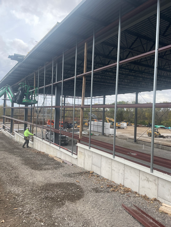 Construction of a building with exposed metal framing. A worker in a lift and another on the ground.
