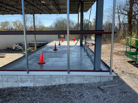 Construction site with a concrete pad and orange traffic cones. Steel framing.