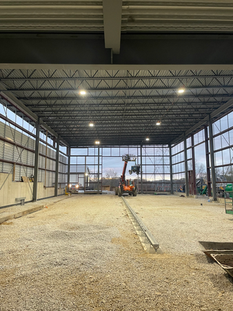 Interior view of a steel-framed building under construction with a lift vehicle in the center.