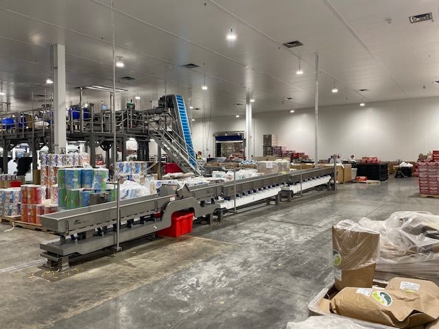 Factory interior with food processing machinery and packaged goods.