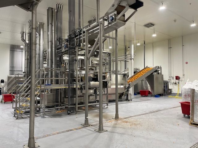Food processing facility with stainless steel equipment and a conveyor belt.