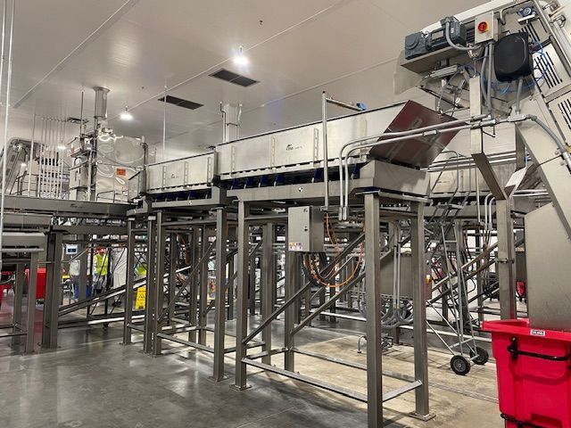 Stainless steel industrial food processing equipment inside a facility.