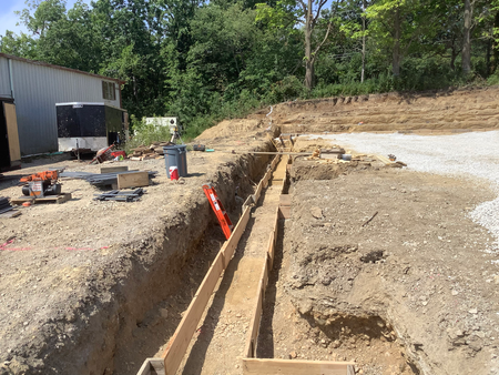 Trench construction with wooden forms, level, and tools outdoors. Building in progress.