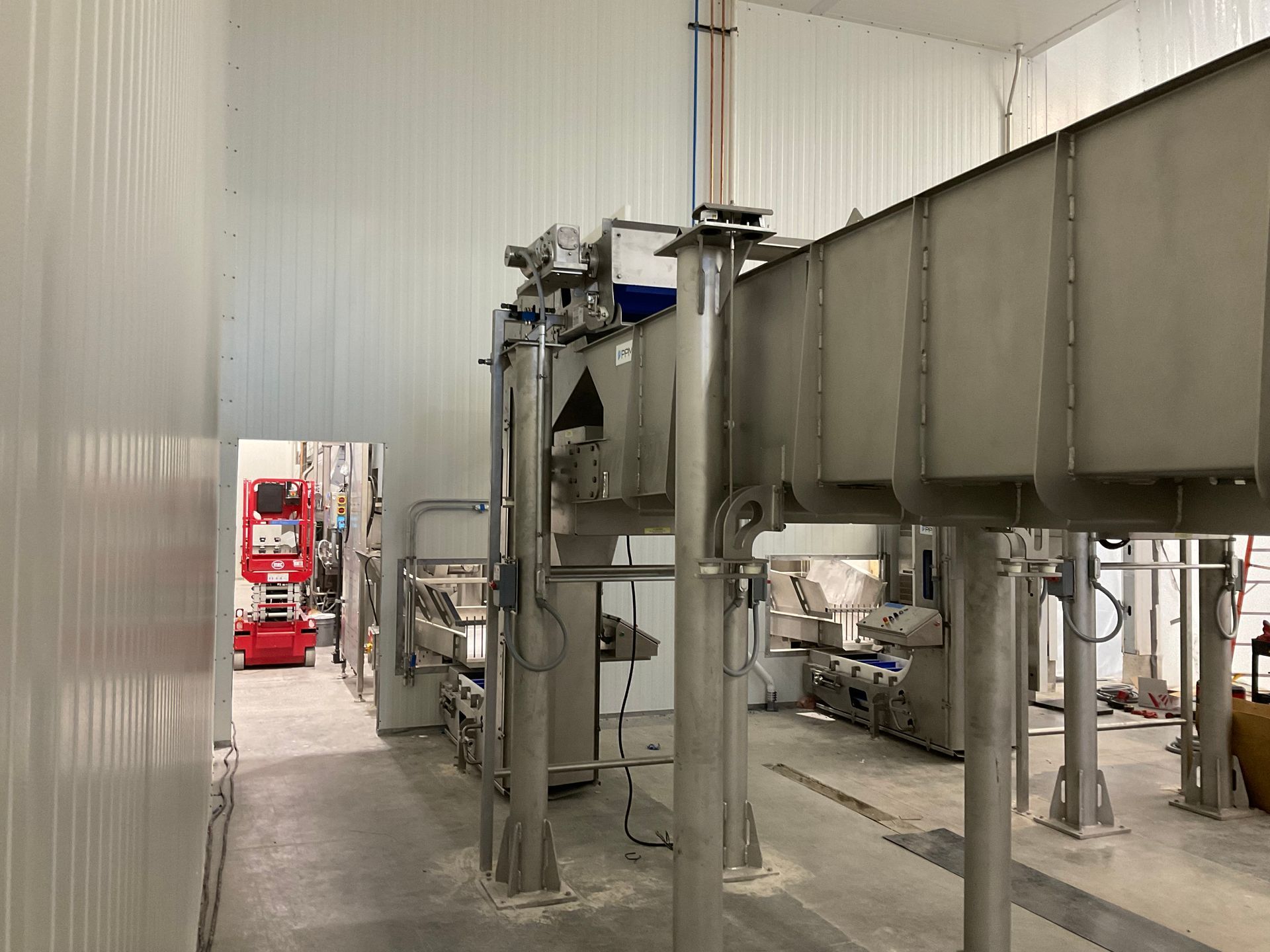 Stainless steel industrial machinery in a white-walled room.