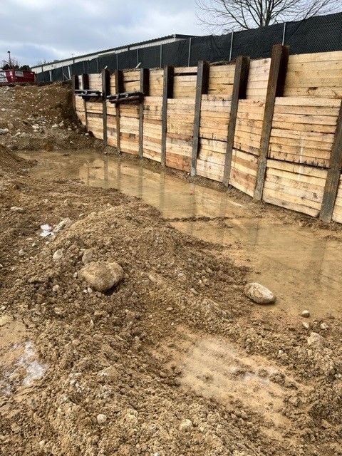 Wooden retaining wall in muddy construction site.