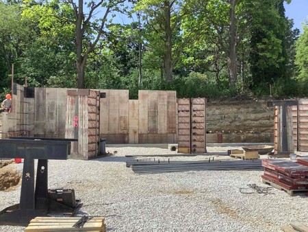 Construction site with concrete forms for a building foundation, rebar, and a worker.