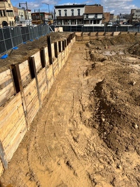 Construction site with wooden retaining wall and excavated earth.