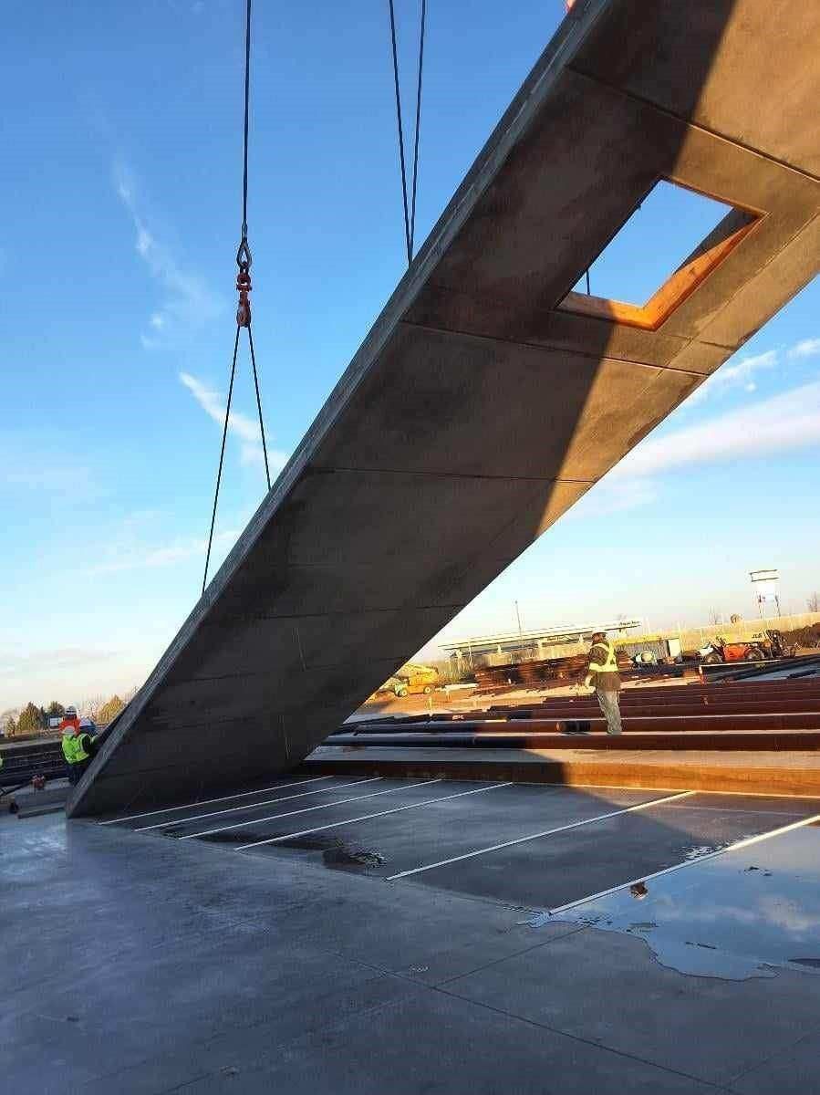 A large concrete slab being lowered onto a prepared surface by a crane at a construction site.