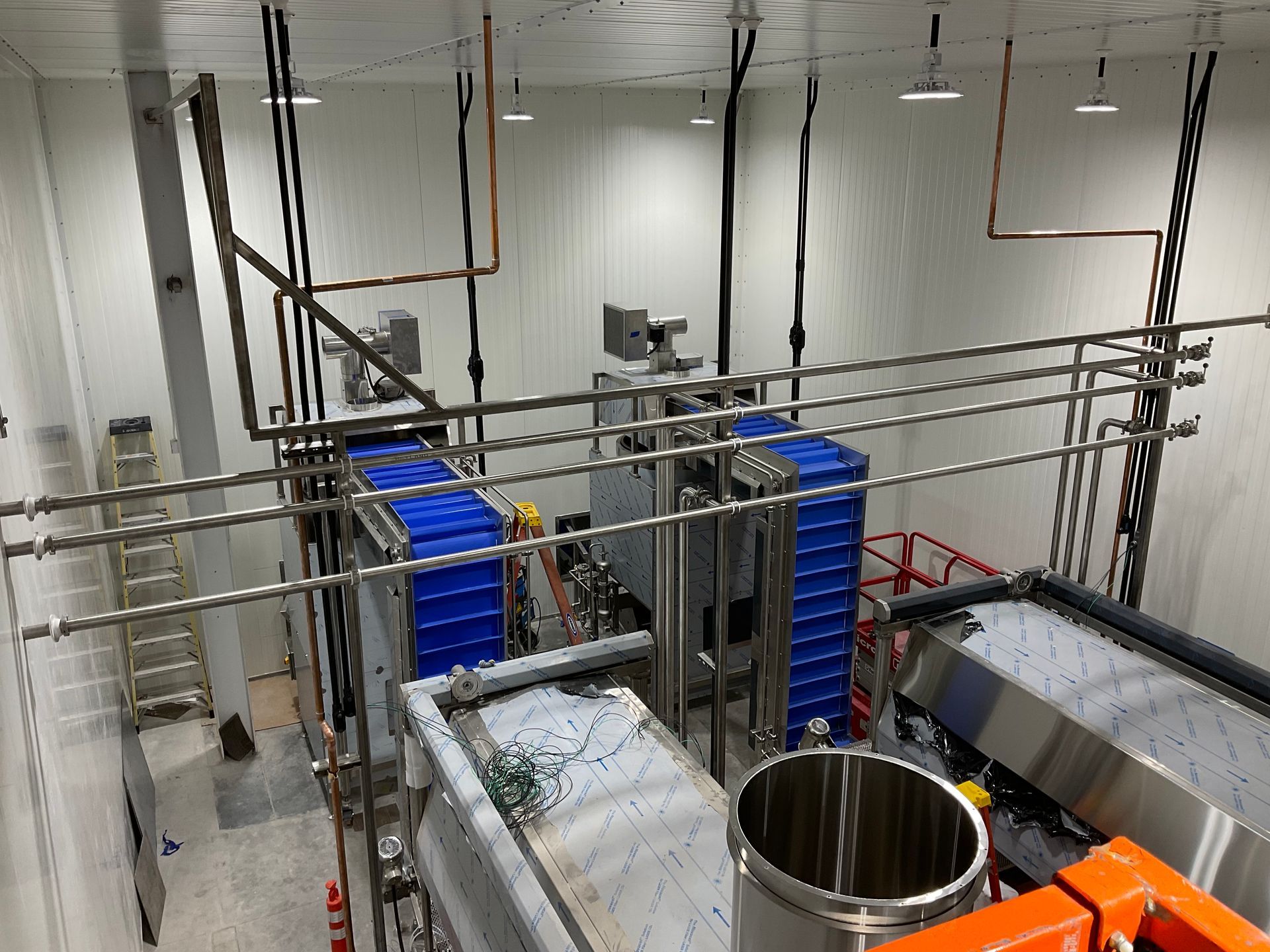 Industrial food processing equipment in a sterile white room with various pipes and conveyors.