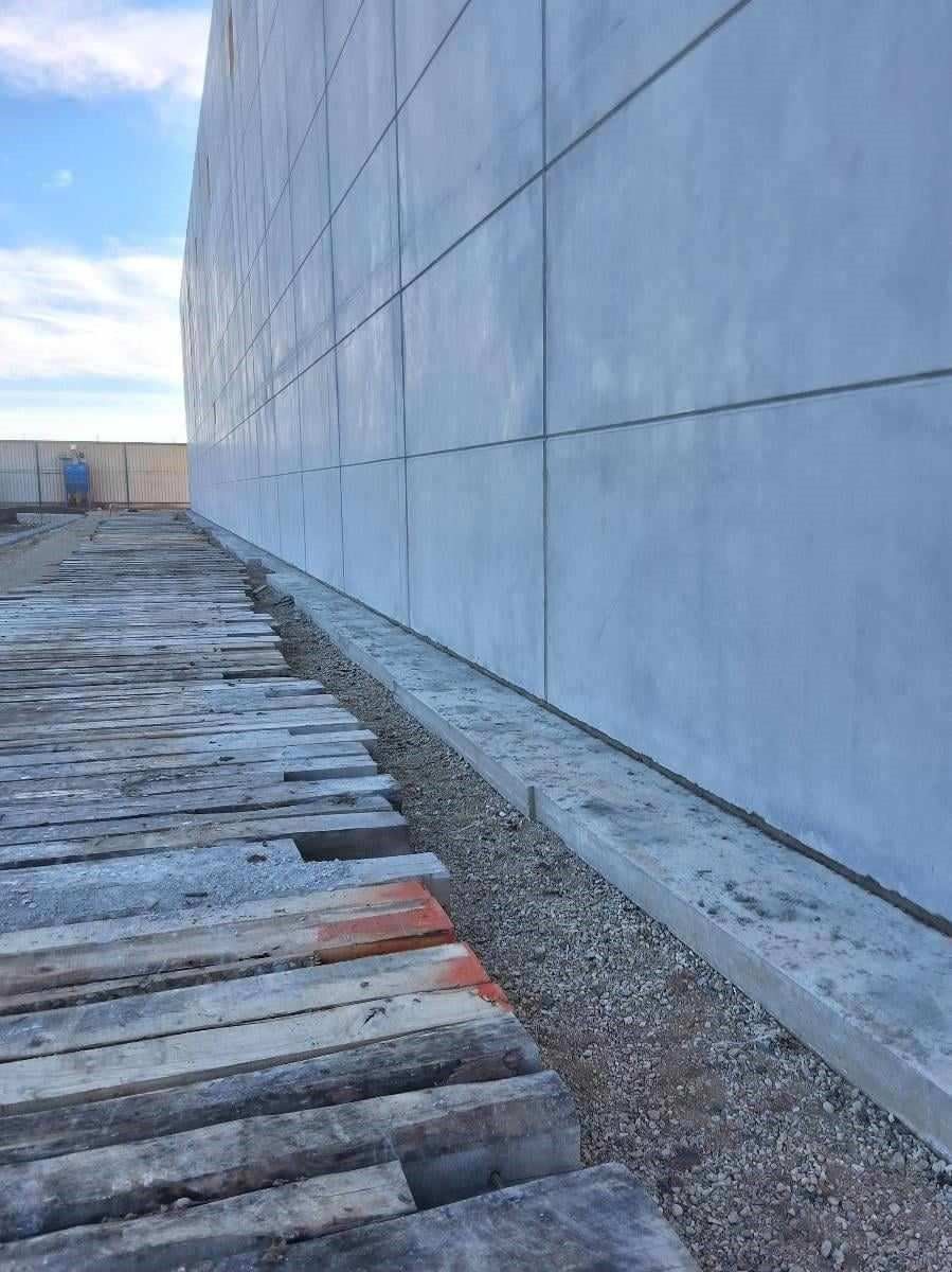 Construction site: Concrete wall with gravel bed and wooden planks.