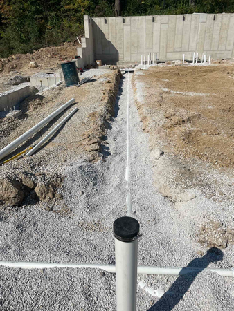 Construction site with trenches, pipes, and concrete foundation.