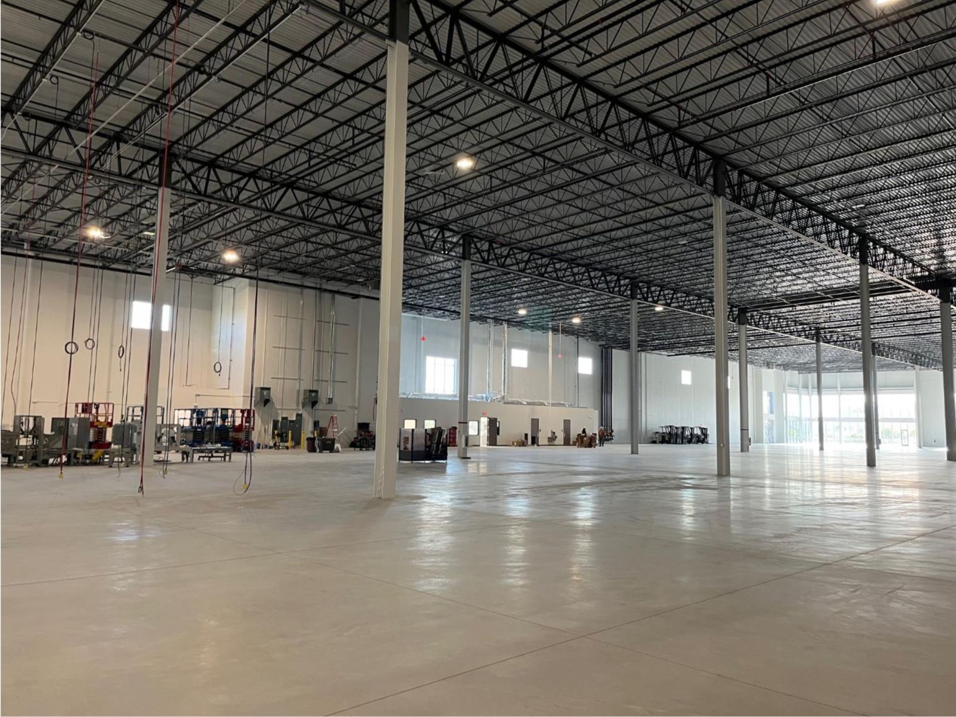 Empty warehouse interior with polished concrete floor, steel columns, and high ceiling lights