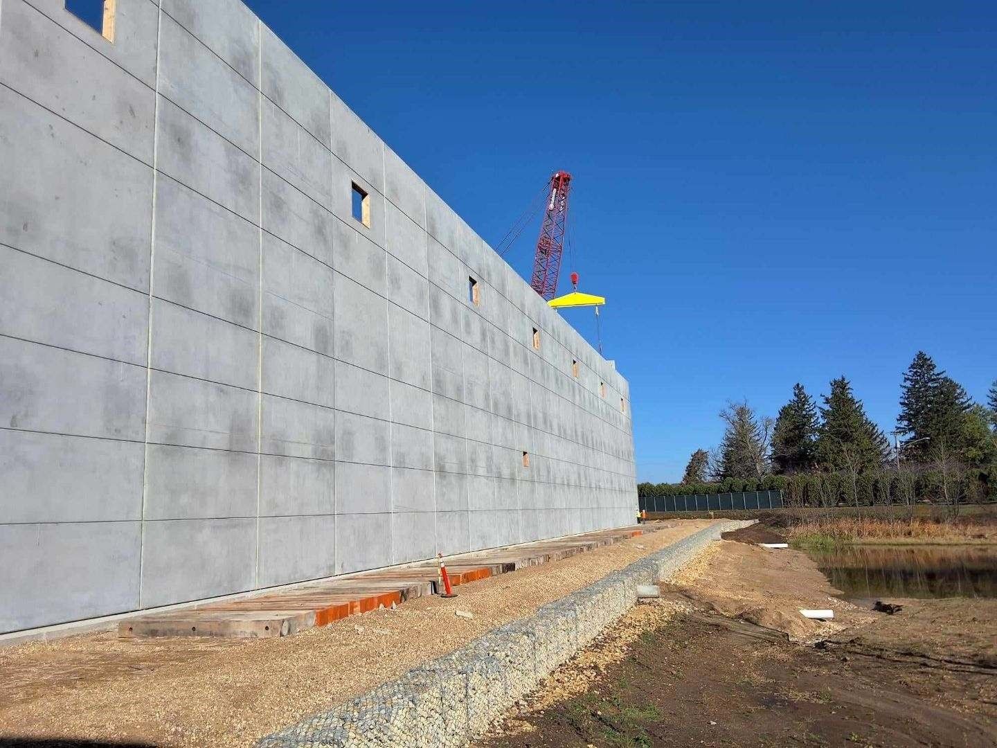 Large concrete building under construction with a crane and clear blue sky.