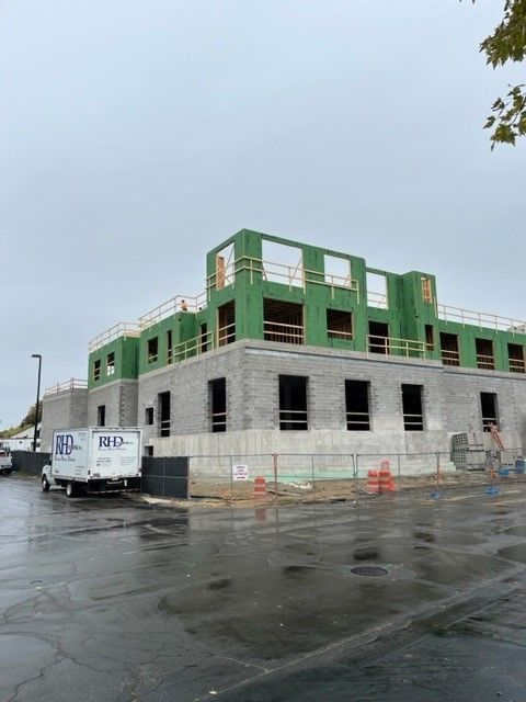 Construction of a multi-story building on a rainy day. Concrete walls and wood framing visible.