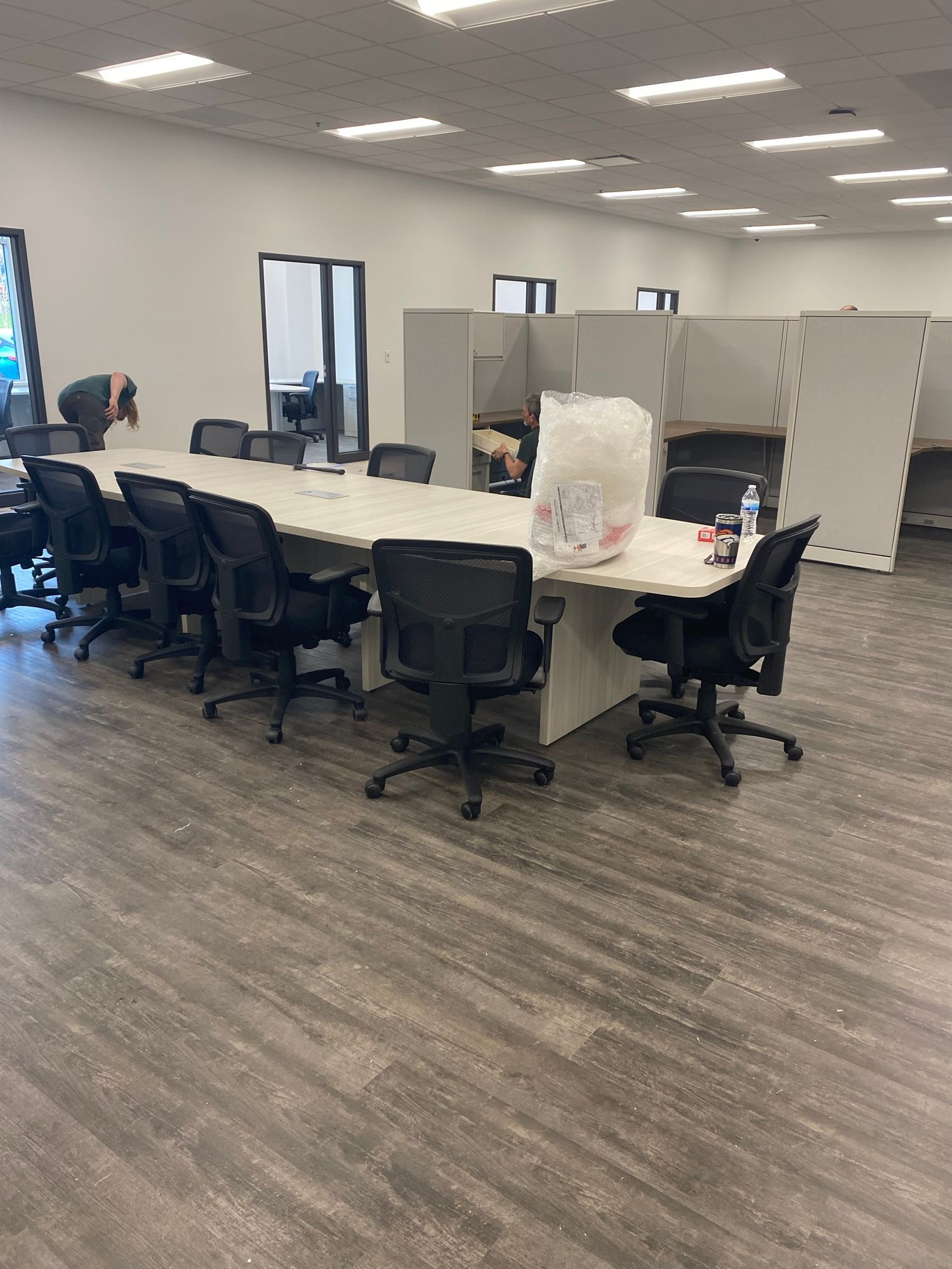 Long rectangular meeting table with black chairs, in a bright, empty office.