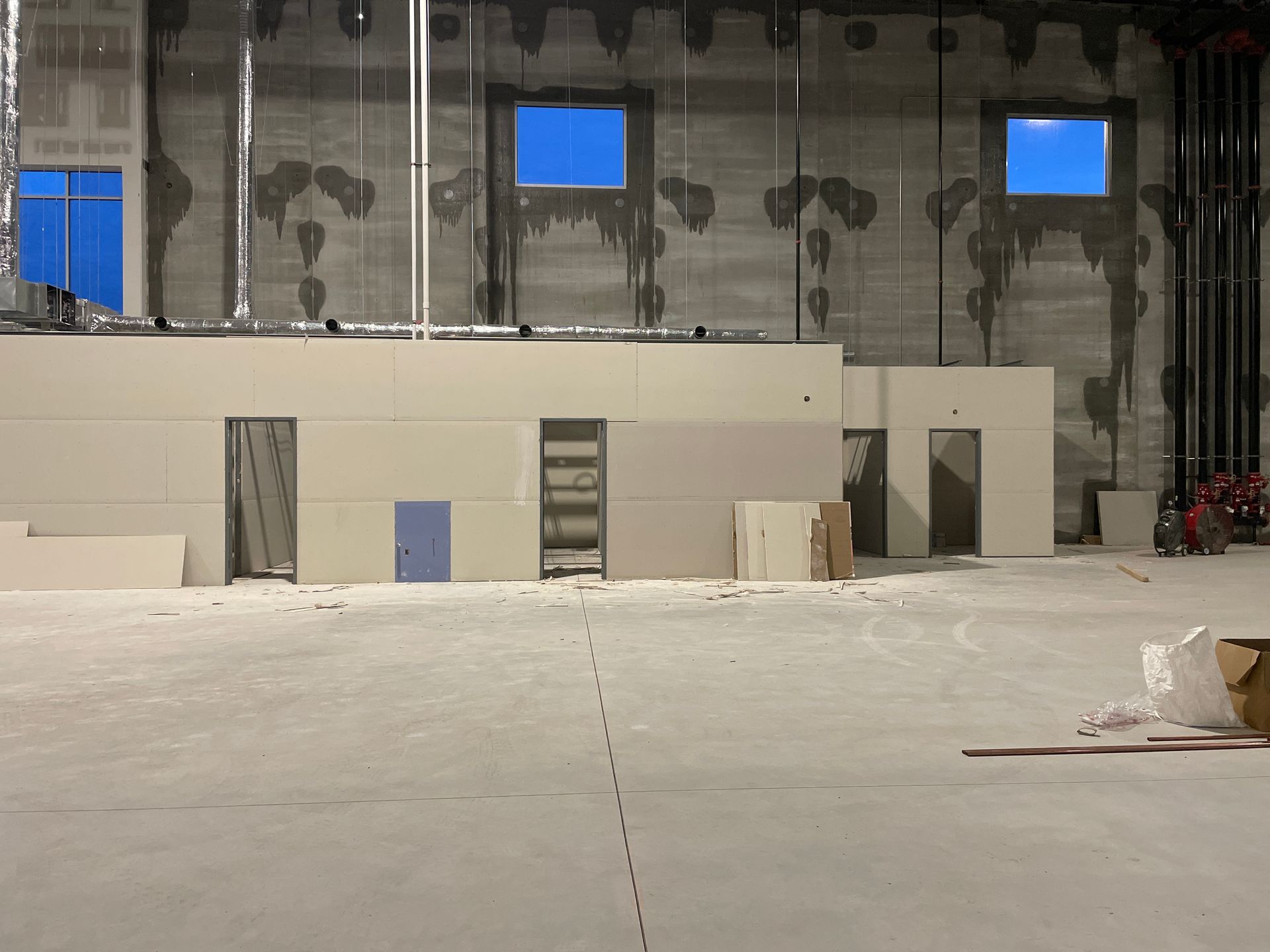 Empty indoor set with beige walls, blue window panels, and unfinished construction materials on the floor.