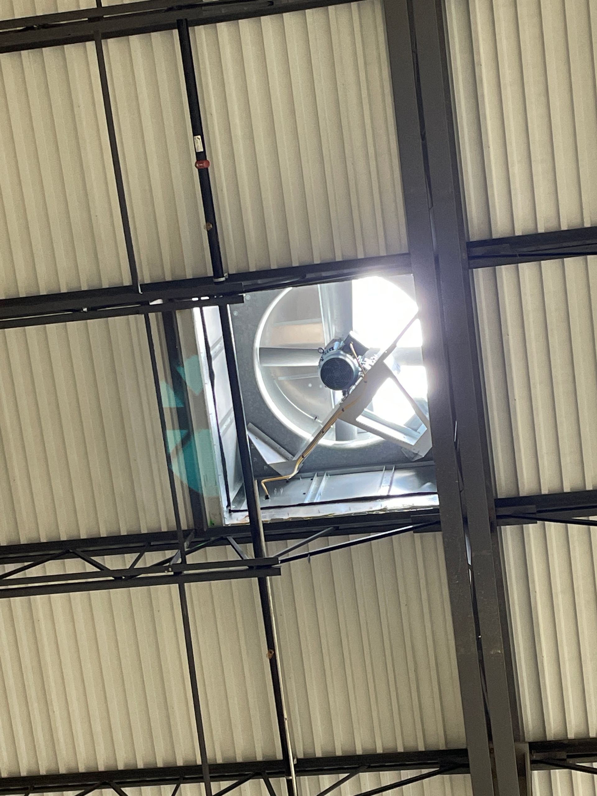 Ceiling with a square exhaust fan and corrugated metal panels in an industrial space