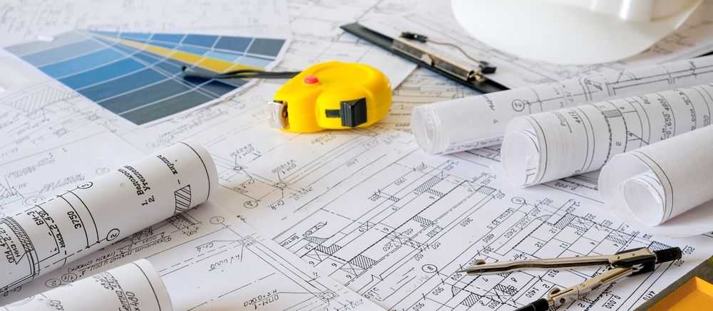 Architectural blueprints with tools, including a tape measure and color swatches.