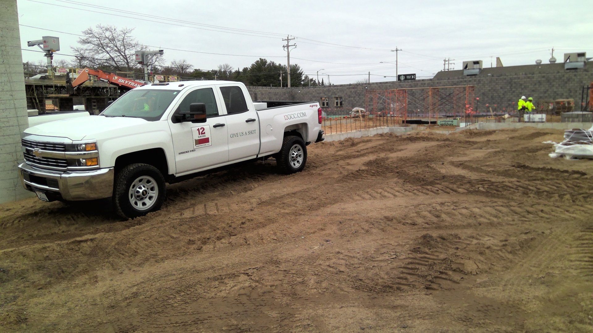 White pickup truck parked on dirt at a construction site.