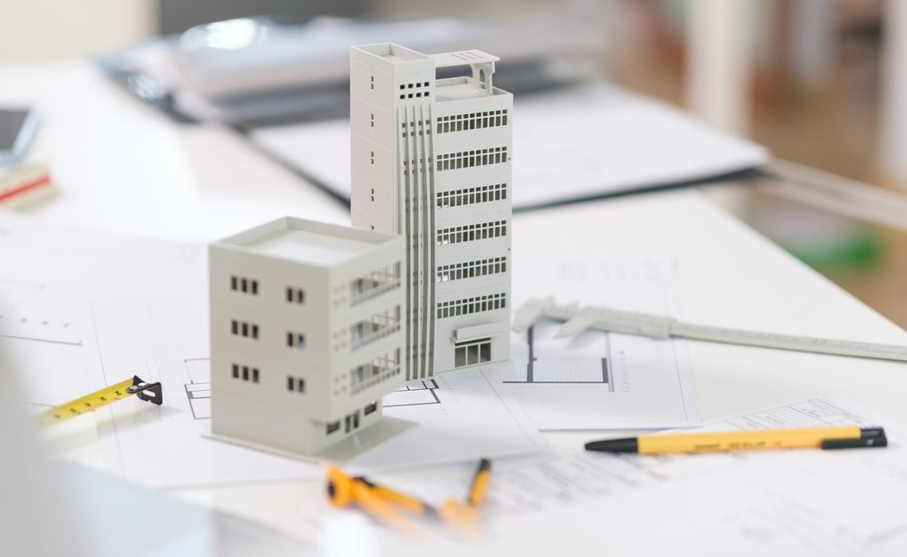 Architectural models on blueprints, with drawing tools, suggesting design planning.