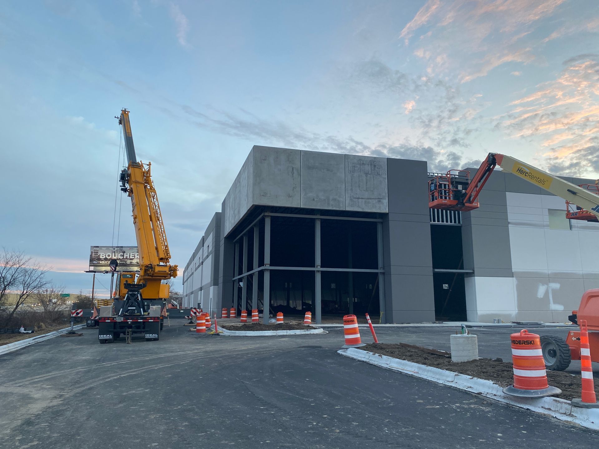 Construction site: crane lifting panel; building facade in progress. Concrete and gray colors.
