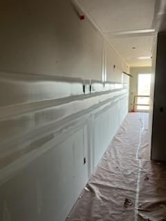 Hallway with partially finished drywall and protective floor covering.