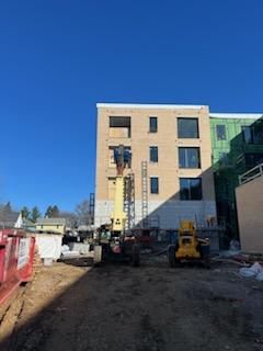 Construction site with a building, machinery, and clear blue sky.