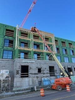 Construction site with a boom lift and crane. Building under construction, blue sky.