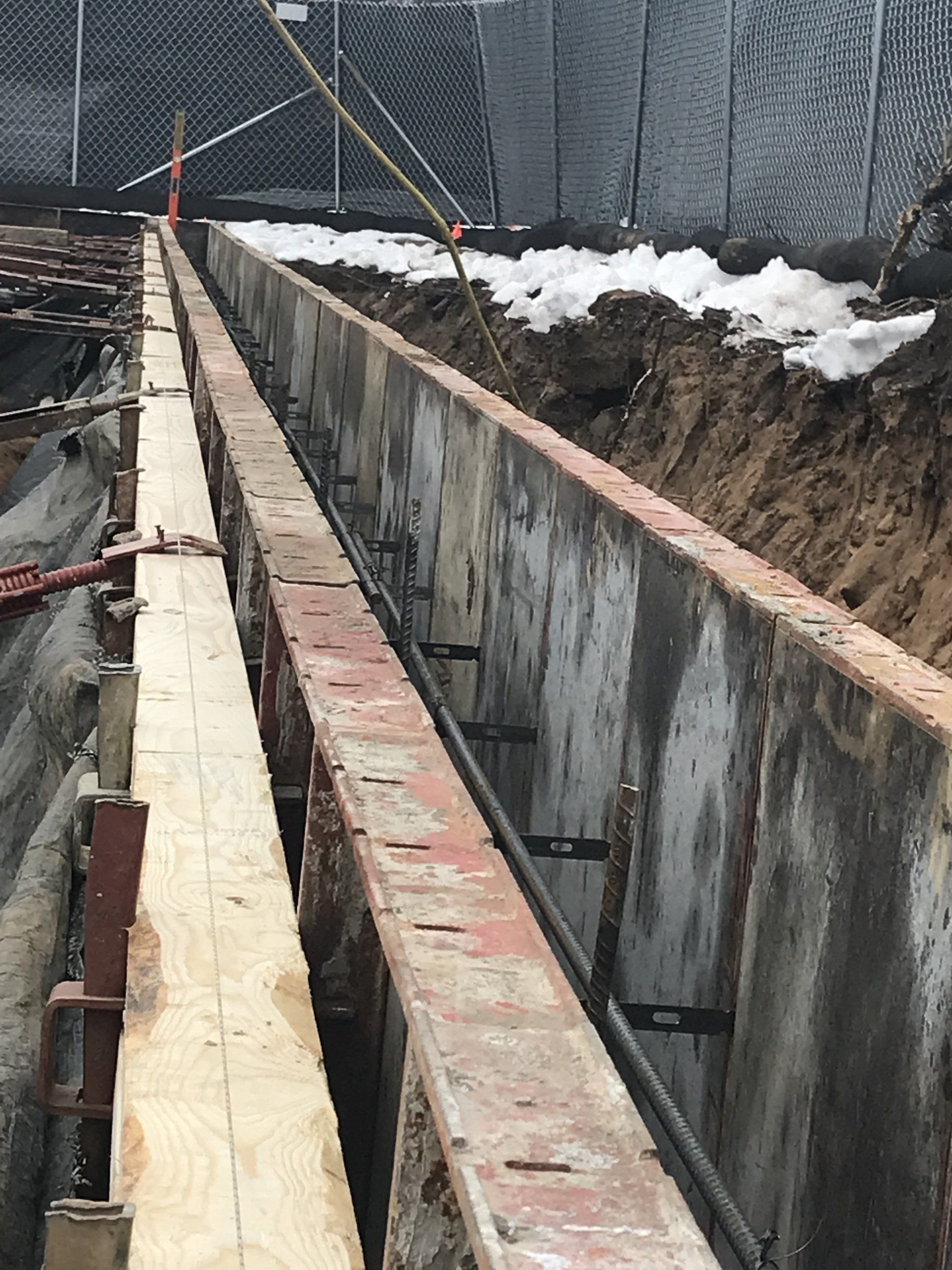 Concrete construction trench with metal bracing and wooden beams.