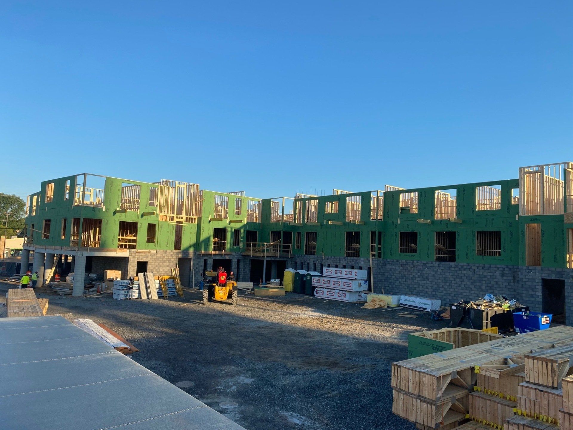 Construction site of a multi-story building, wood frame and stone exterior, clear sky.