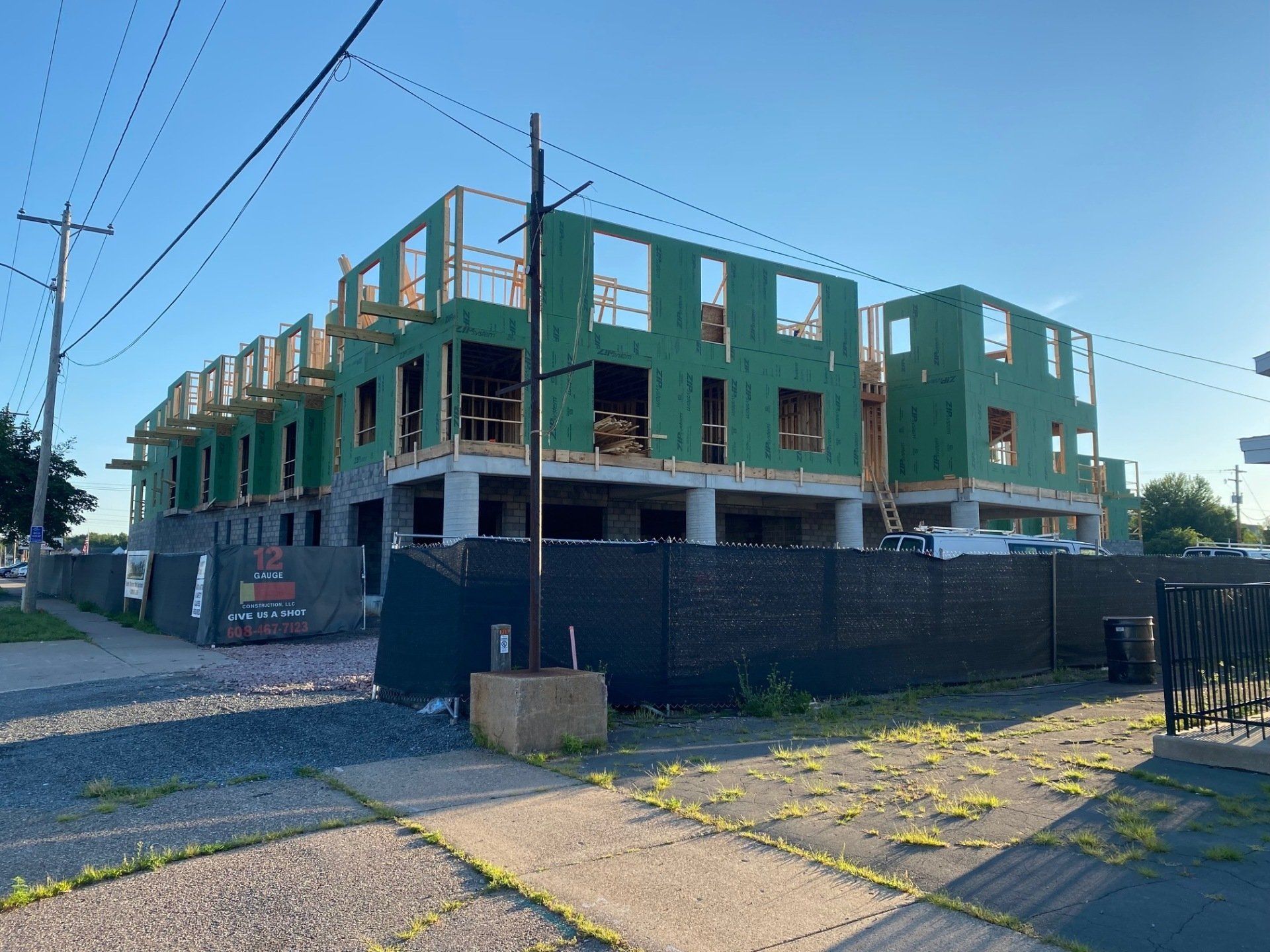 Building under construction with wooden framing and a black fence in front.
