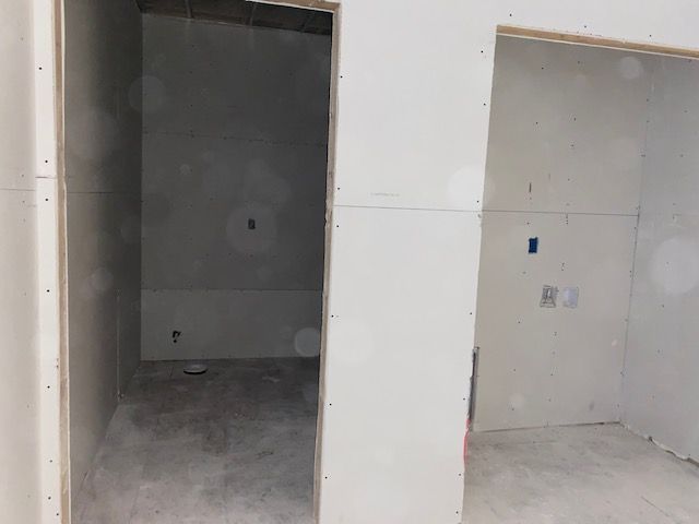 Two unfinished rectangular rooms with drywall walls and a concrete floor.