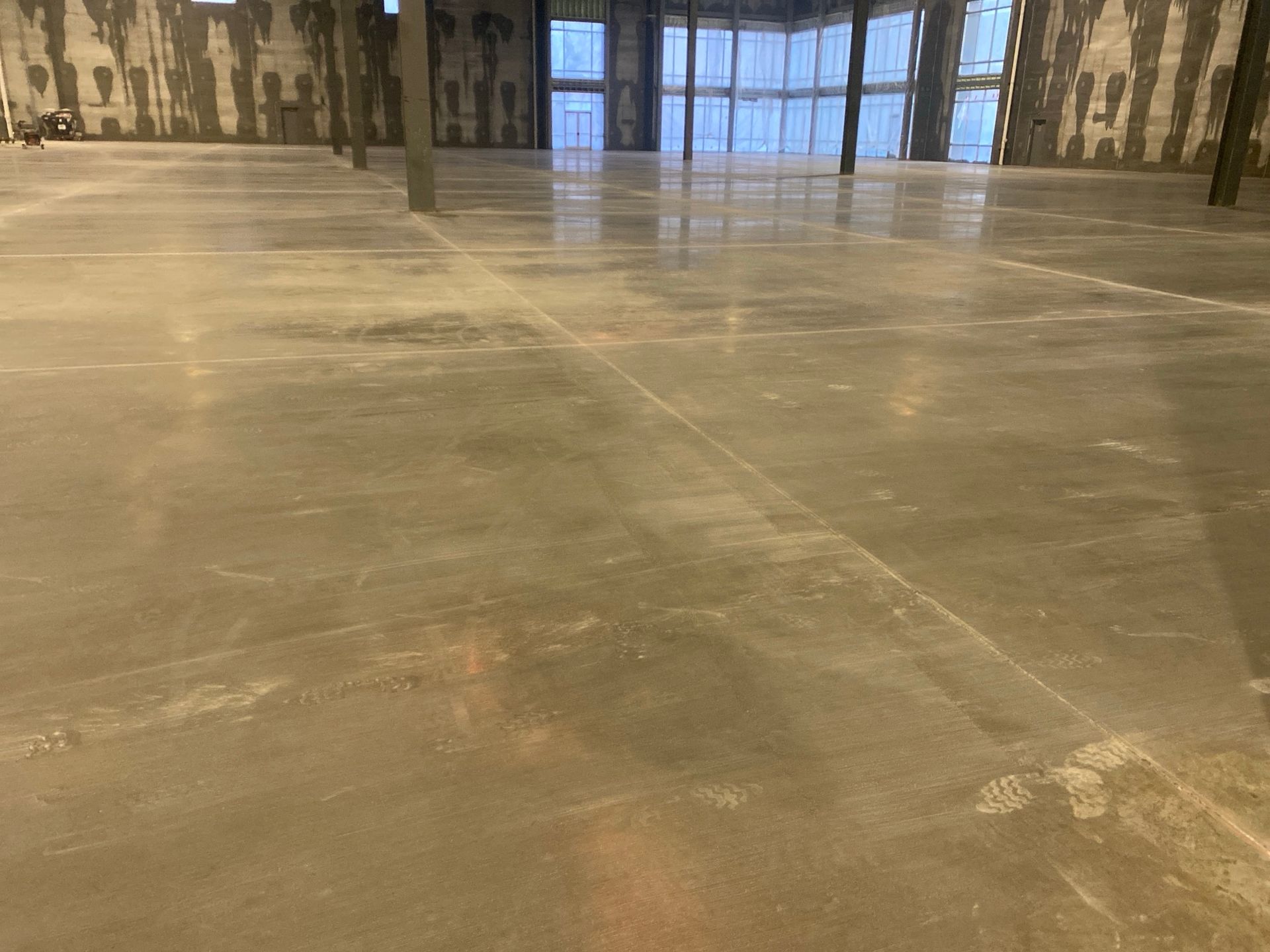 Empty interior of a building with a large polished concrete floor and visible support columns.