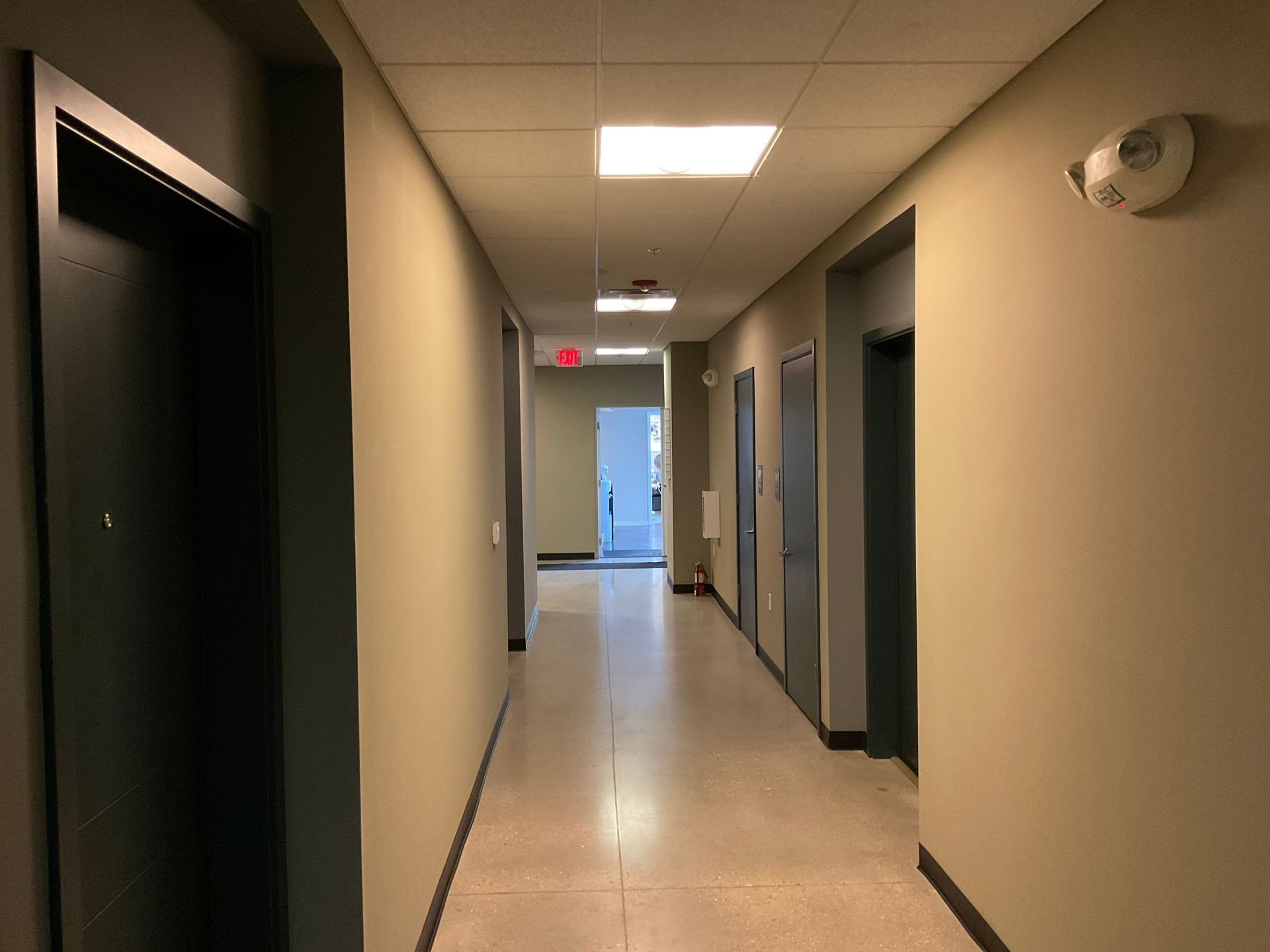 Long hallway with several closed doors and overhead lighting.