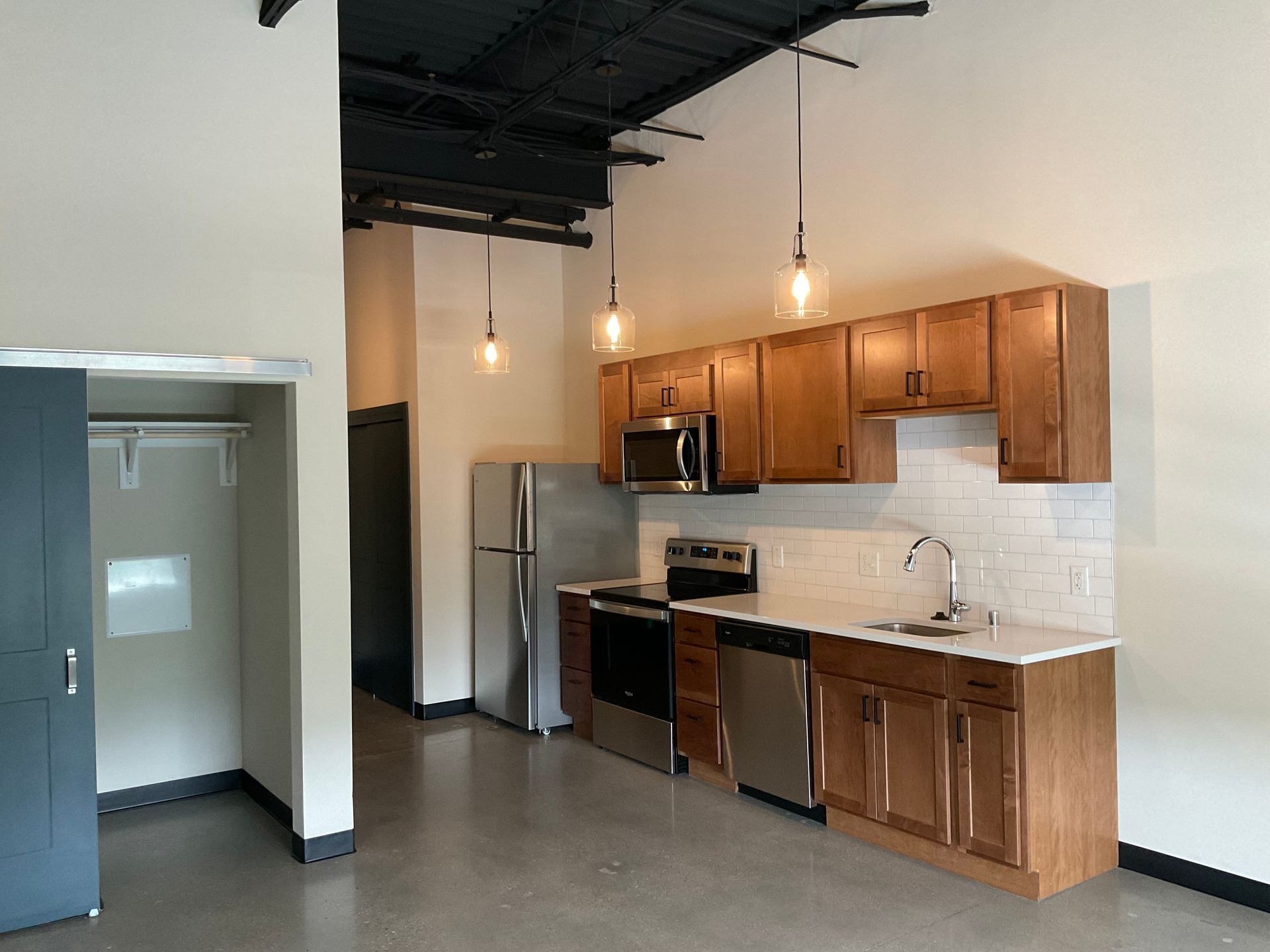 Modern kitchen with stainless steel appliances, light wood cabinets, and pendant lights.