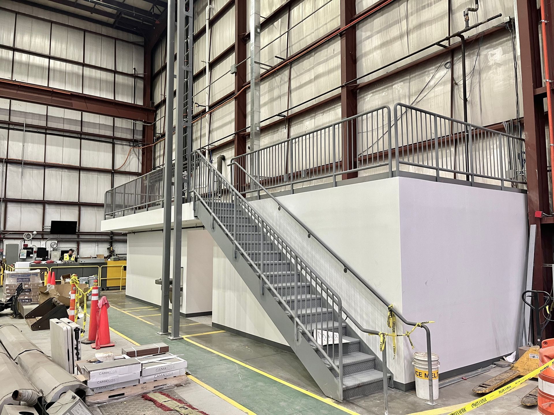 Metal staircase leading up to a platform inside a large industrial building.