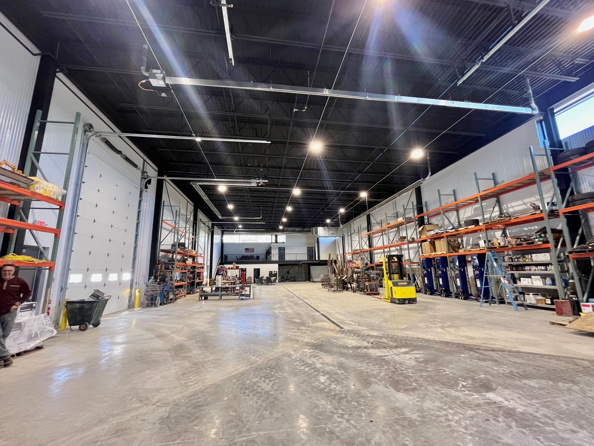 Interior warehouse with shelving, a forklift, and loading bays.