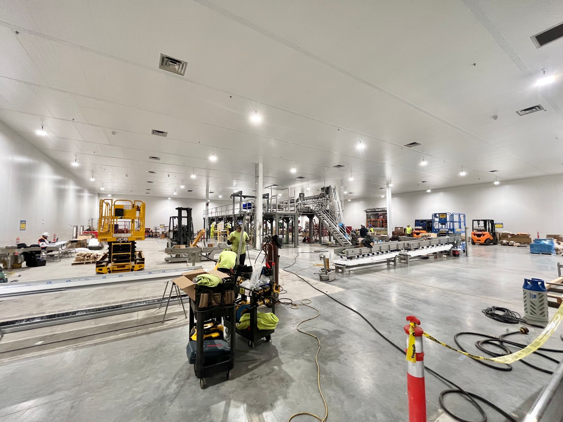 Large industrial factory space under construction, with machinery, equipment, and workers.