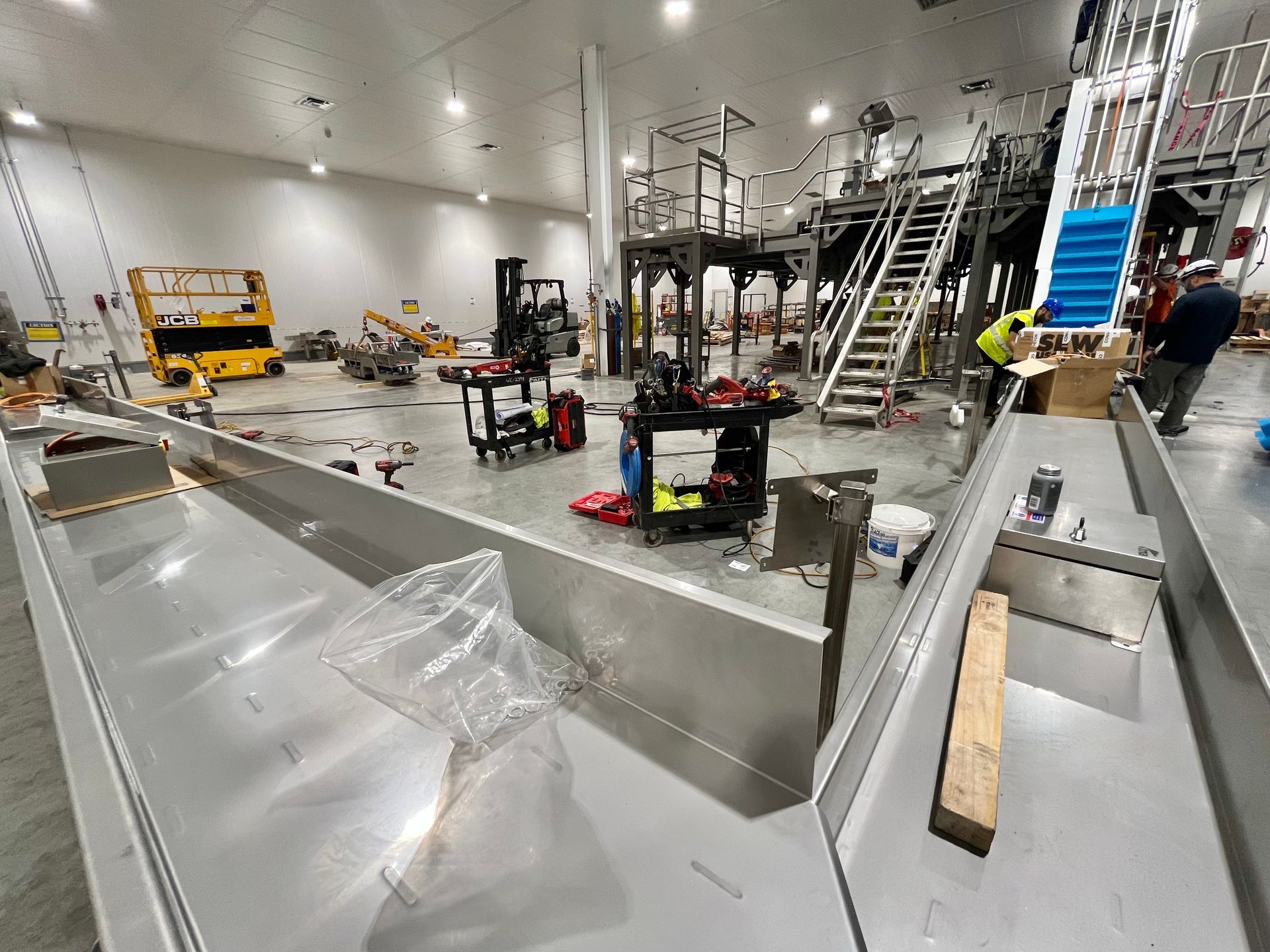 Large factory floor with machinery under construction, workers present.
