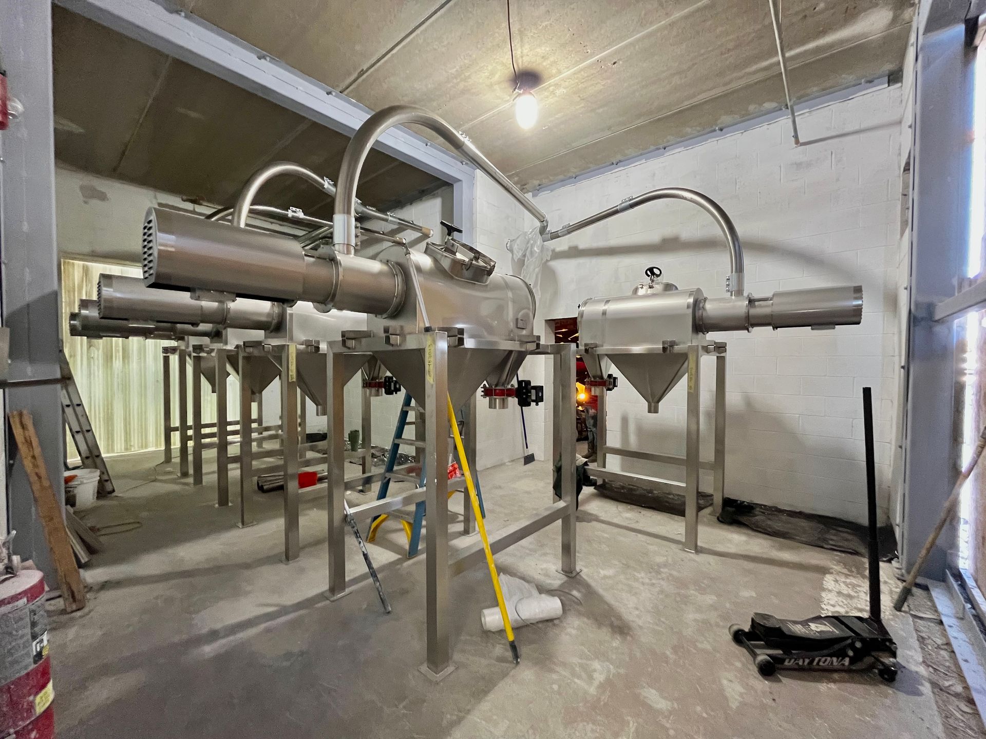 Stainless steel industrial processing equipment in a construction setting.