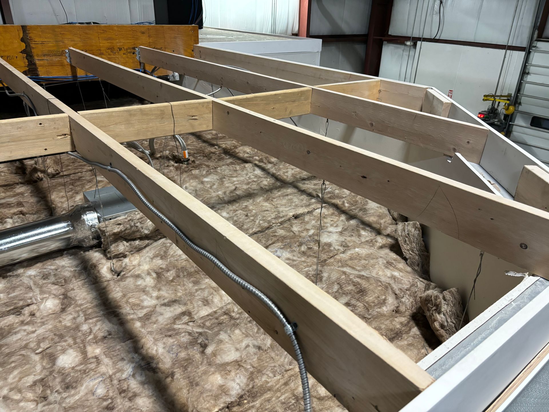 Wooden frame construction on top of insulation within a building.